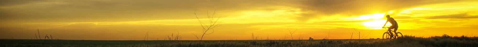 Radreisen - Fahrradfahrer zum Sonnenuntergang (Panorama)